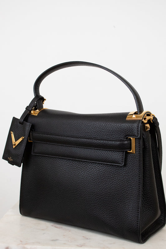 Black handbag with gold accents on a light gray background