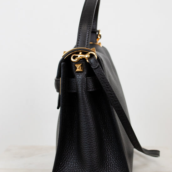 Black leather handbag with gold hardware on a white background