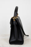 Black leather handbag with gold hardware on a white background