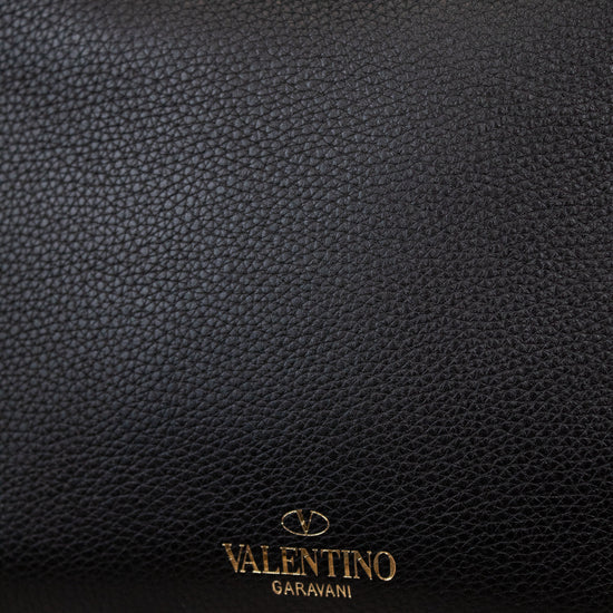 Black leather handbag with 'Valentino Garavani' logo on a marble surface