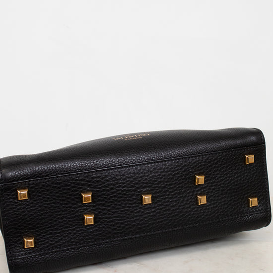Black leather bottom of purse with gold studs on a marble surface