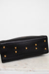 Black leather bottom of purse with gold studs on a marble surface