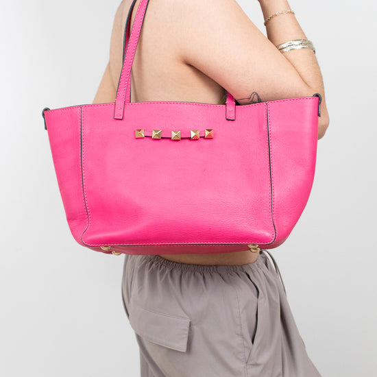 Person holding a bright pink tote bag against a white background