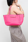 Person holding a bright pink tote bag against a white background