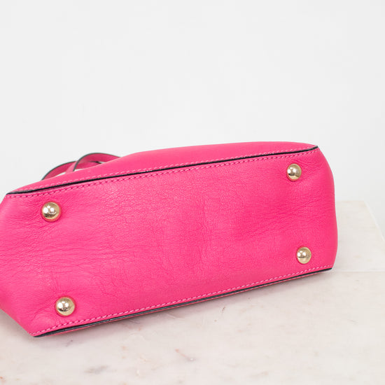 Pink handbag with gold studs on a light pink background
