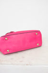 Pink handbag with gold studs on a light pink background