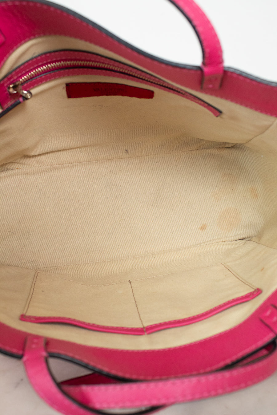 Close-up of a pink handbag with visible wear on the interior.