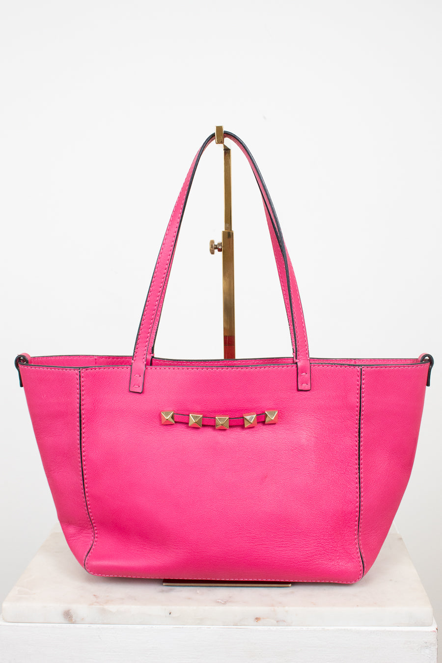 Pink handbag with gold accents on a white background
