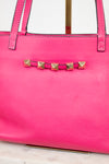Pink handbag with gold stud details on a light background