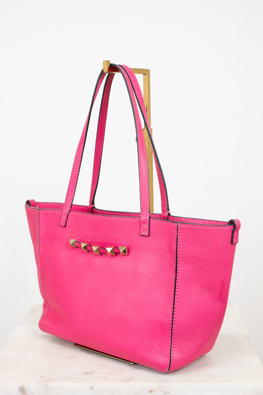 Pink tote bag with gold accents on a white background