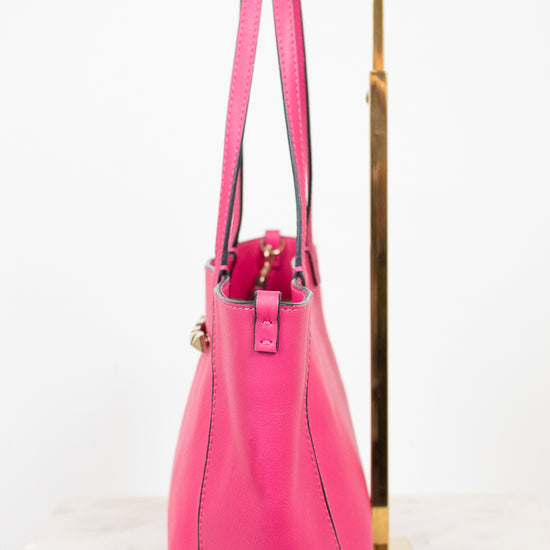 Pink handbag on a gold stand against a white background
