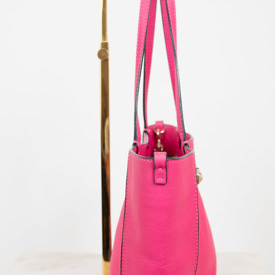 Pink handbag on a gold stand against a white background