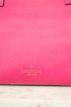 Pink leather handbag with Valentino logo on a light marble surface