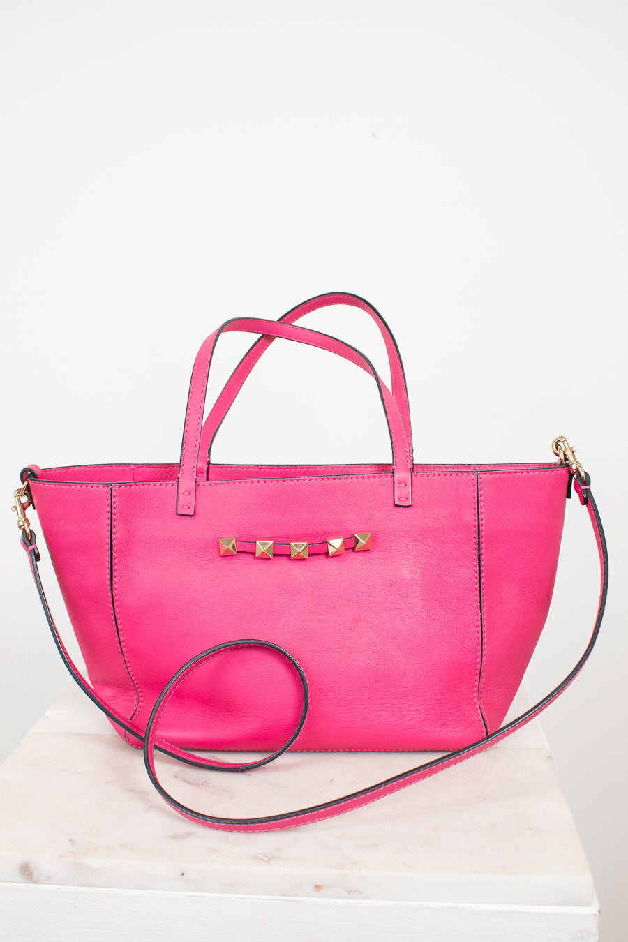 Pink handbag with gold accents on a white background