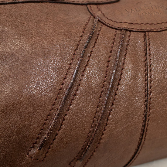 Close-up of a brown leather bag with visible stitching on a marble surface