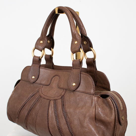 Brown handbag with gold accents on a white background