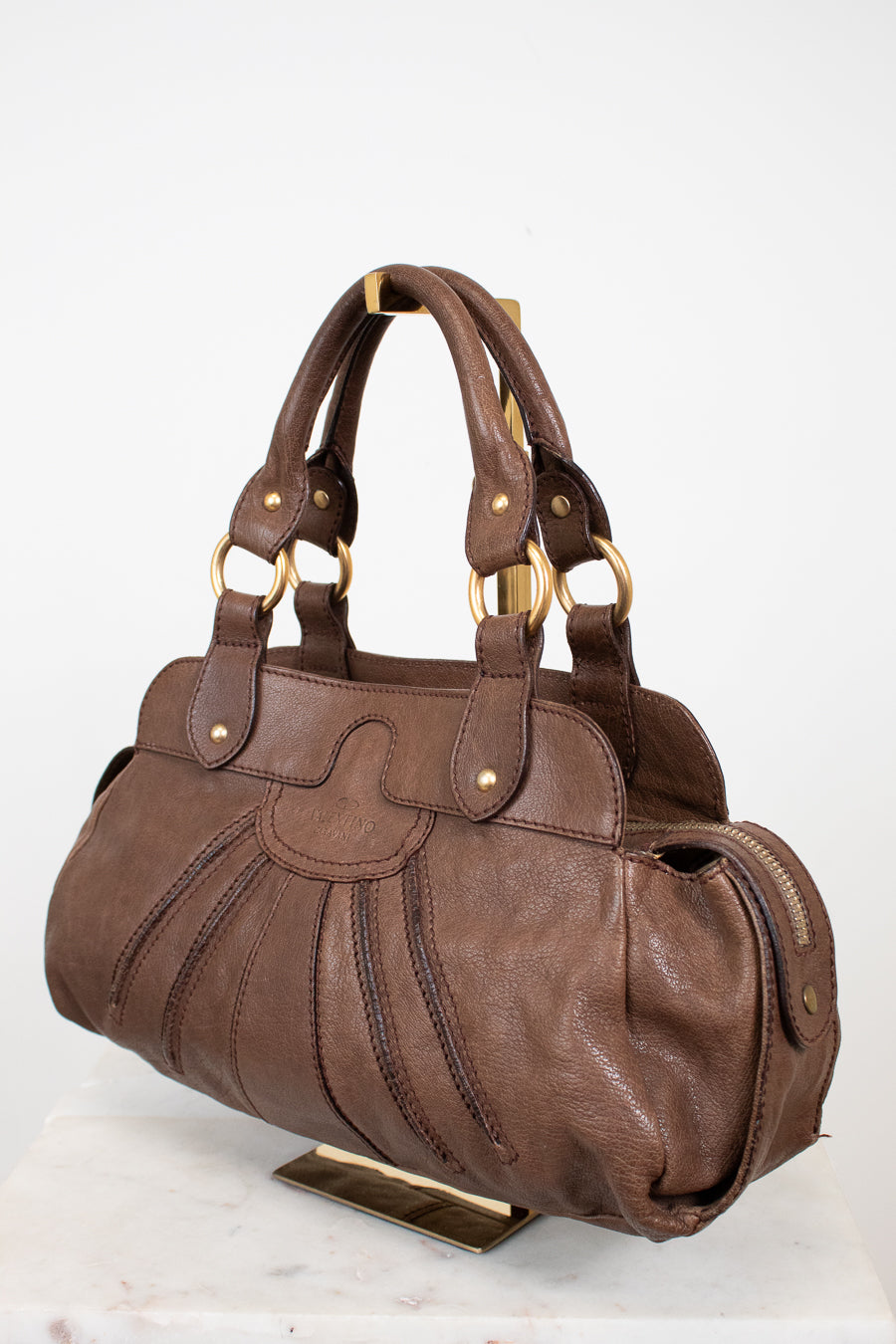 Brown handbag with gold accents on a white background