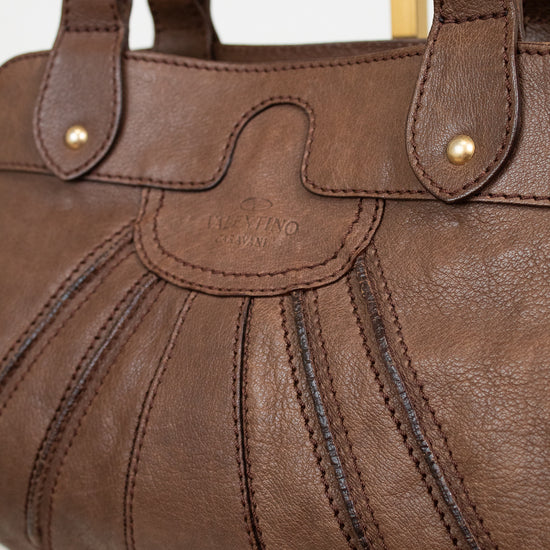 Brown leather handbag with gold accents on a white background