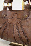 Brown leather handbag with gold accents on a white background