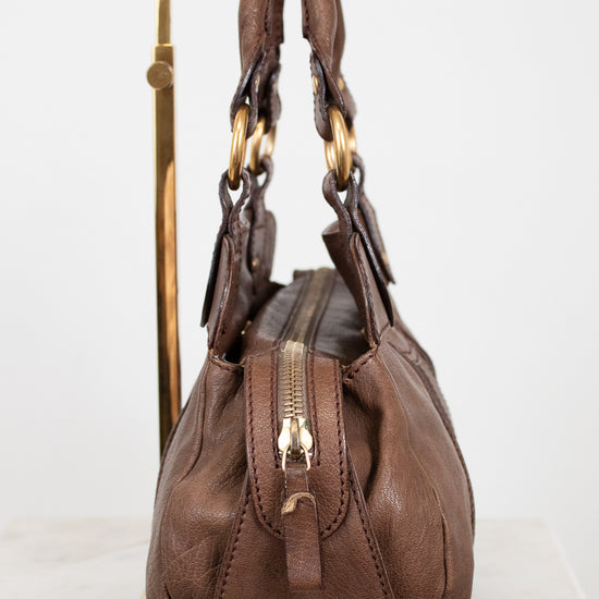 Brown handbag with gold accents on a white background