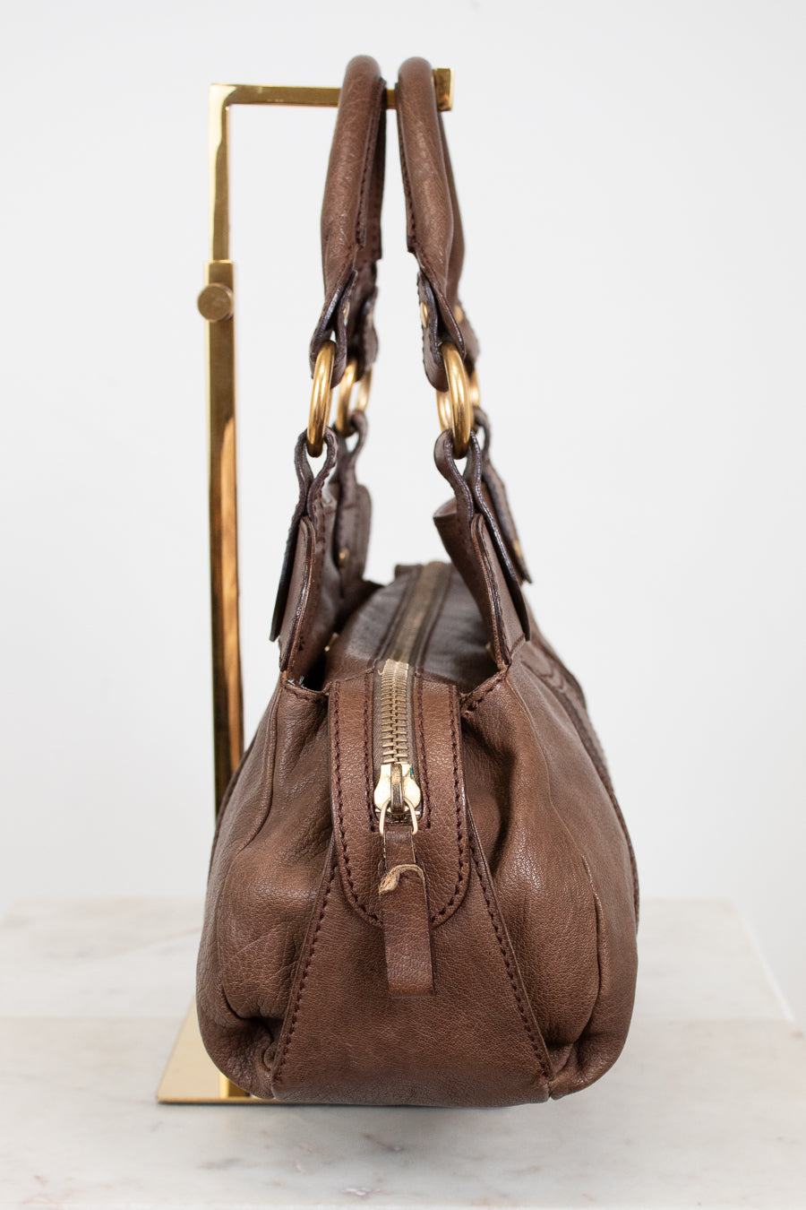 Brown handbag with gold accents on a white background