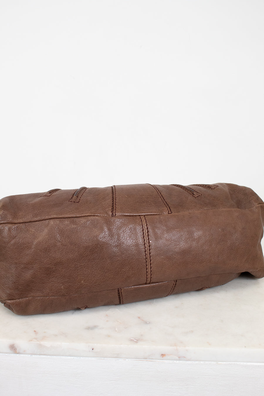 Brown leather bag on a white marble surface
