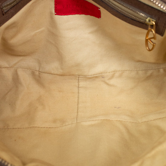 Close-up of a brown leather bag with a gold zipper and red logo tag