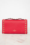 Back close-up view of red rectangular leather bag decorated with gold-tone rock-stud details and top handle against a plain background
