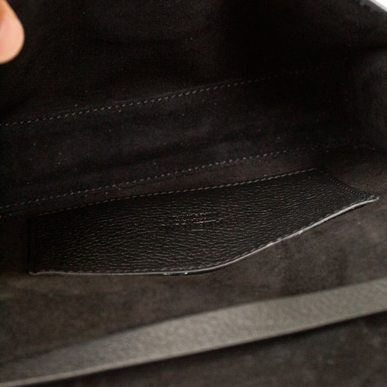 Close-up of a black leather bag with a hand holding it open.