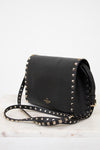 Black handbag with gold studs on a white background