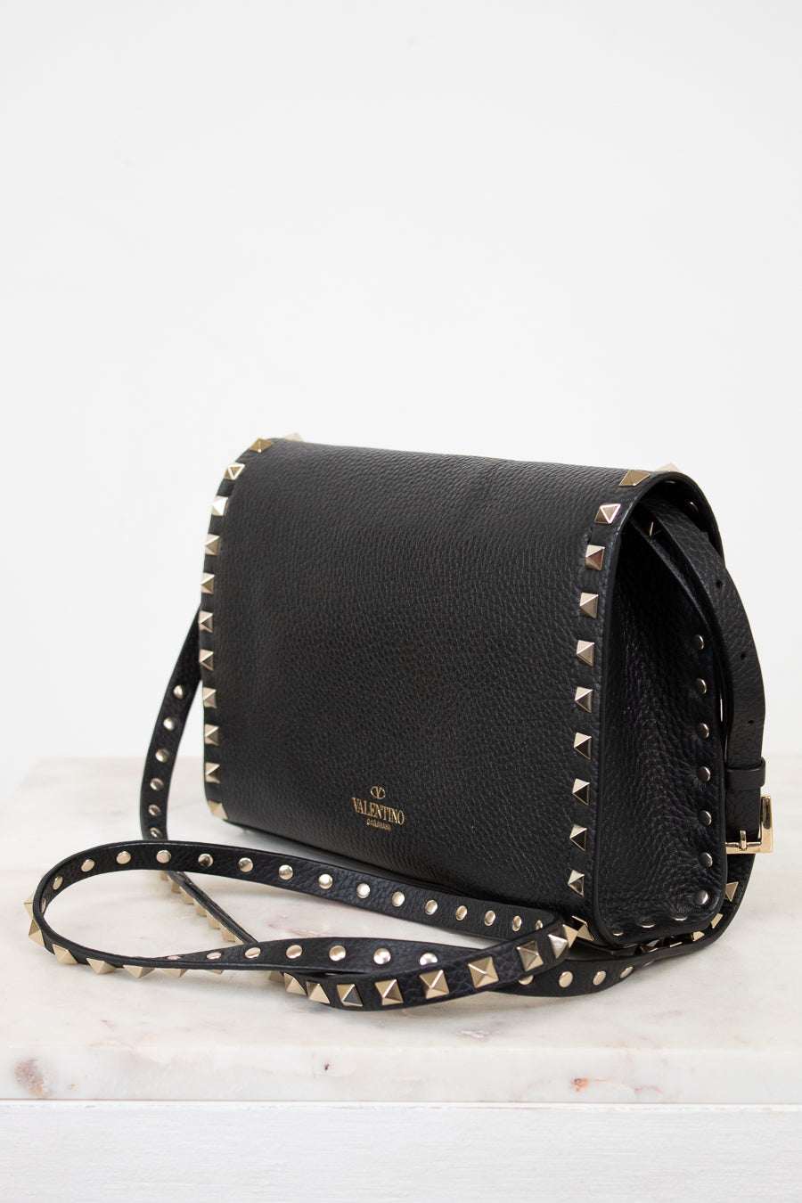 Black handbag with gold studs on a white background