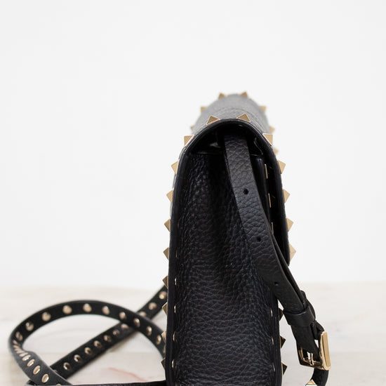 Black studded handbag with a strap on a white background