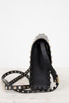 Black studded handbag with a strap on a white background