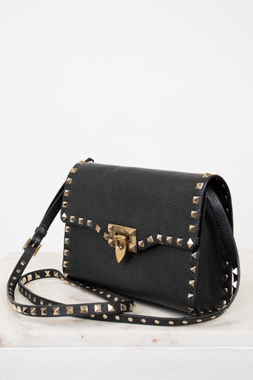 Black handbag with gold studs and a clasp on a white background