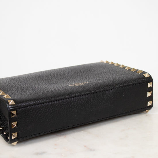 Black wallet with gold accents on a light marble surface