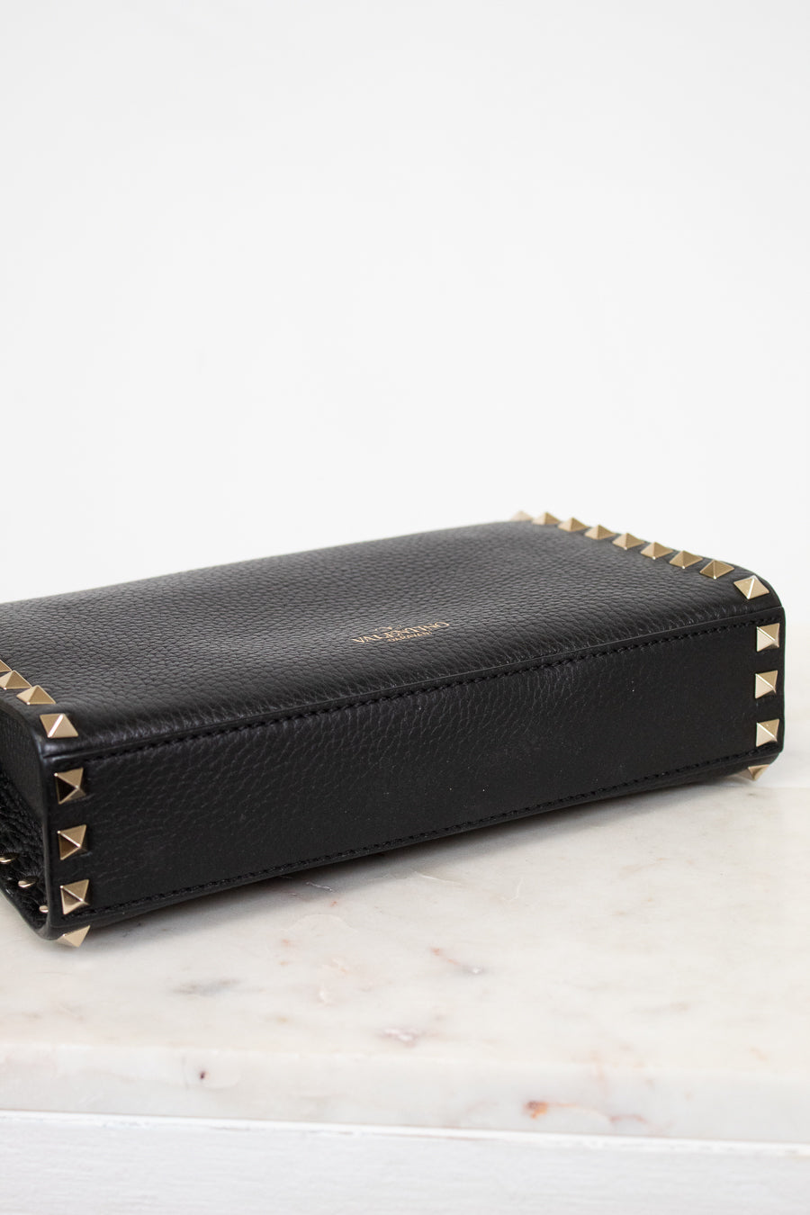 Black wallet with gold accents on a light marble surface