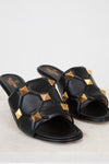 Black sandals with gold studs on a light background