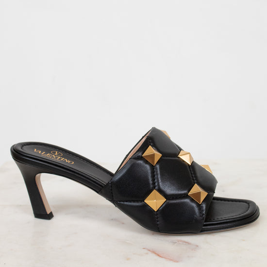 Side view of black leather heels with gold studs on white background
