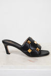 Side view of black leather heels with gold studs on white background