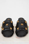 Black slides with gold pyramid studs on a light background
