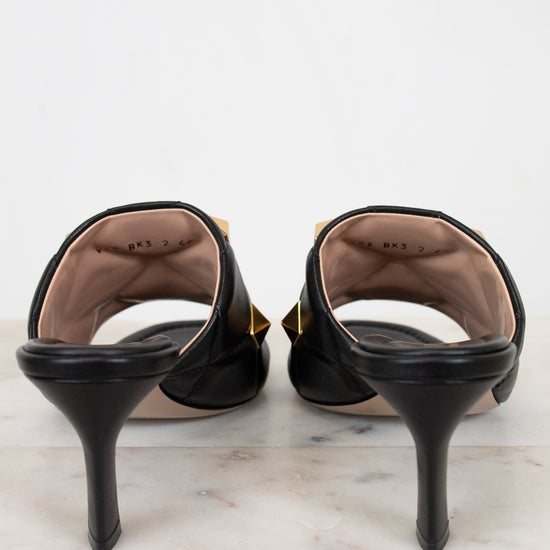 Black high-heeled shoes on a marble surface with a white background