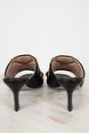 Black high-heeled shoes on a marble surface with a white background