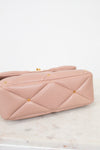 Pink quilted handbag with gold studs on a marble surface