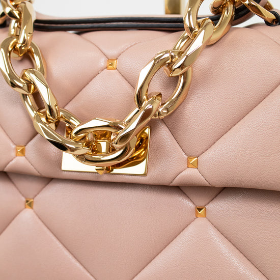 Pink handbag with gold chain detail on a light background