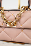 Pink handbag with gold chain detail on a light background