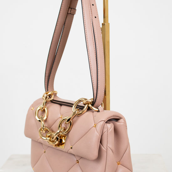 Pink handbag with gold chain detail on a white background