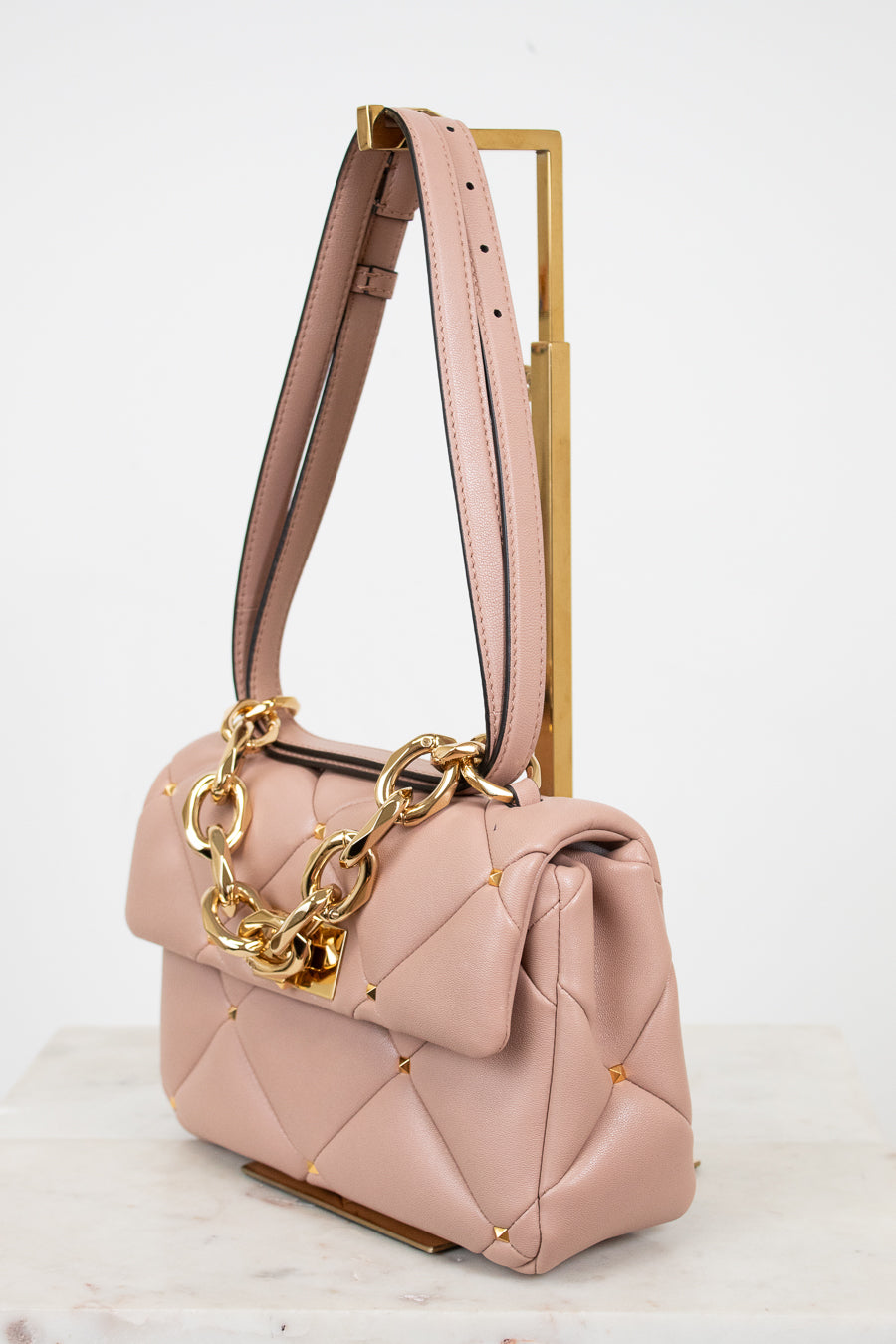 Pink handbag with gold chain detail on a white background