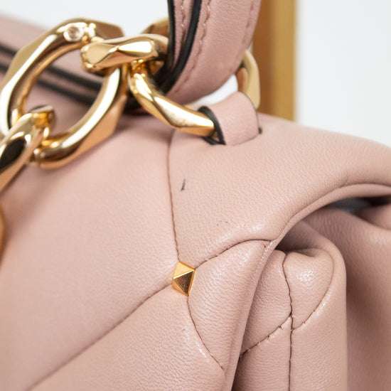 Close-up of a pink handbag with a gold chain detail on a light gray background