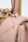 Close-up of a pink handbag with a gold chain detail on a light gray background