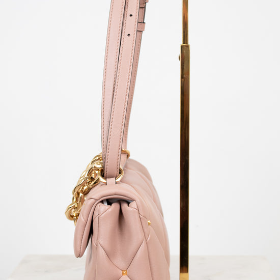 Pink handbag with gold chain detail on a white background